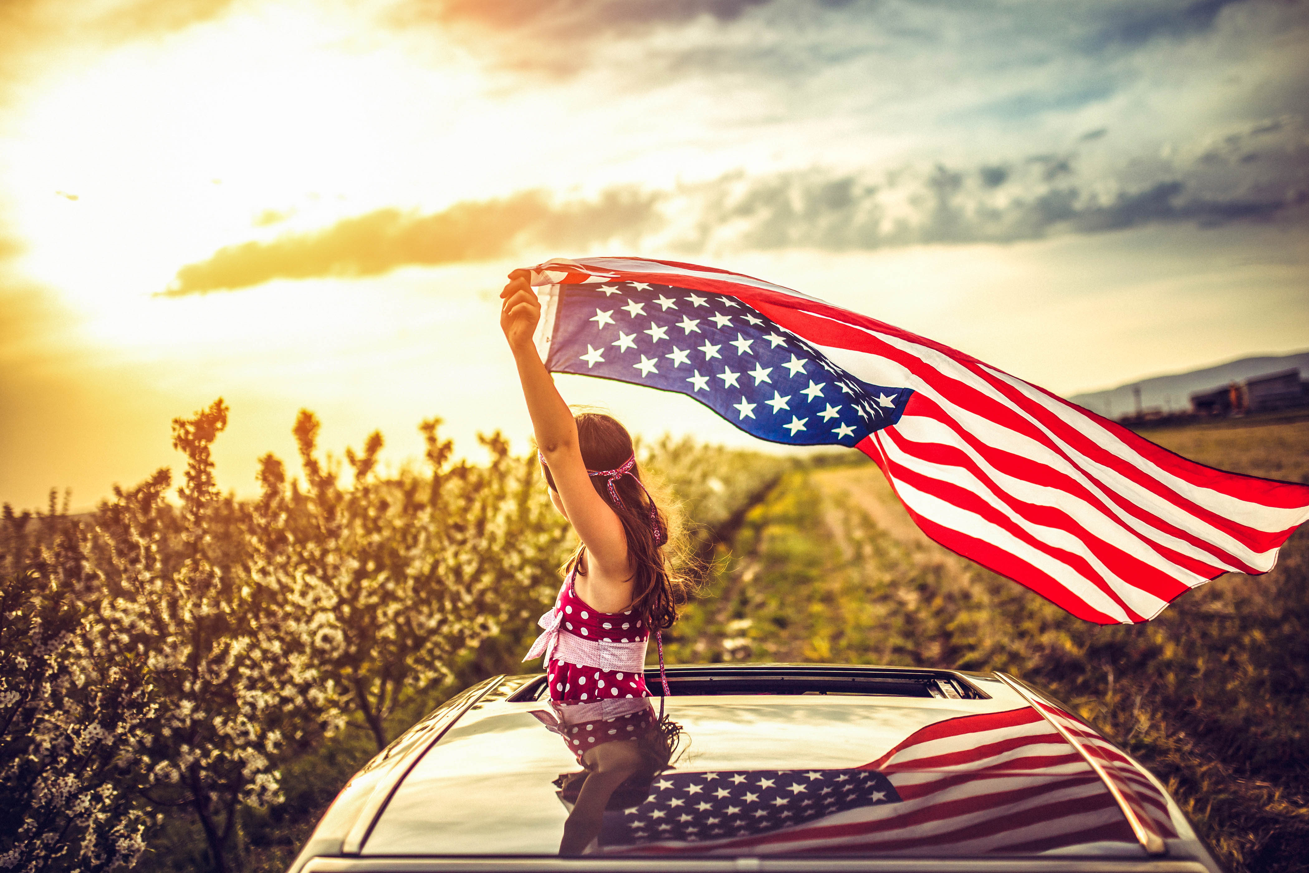 Girl Through a Car Sunroof Waving with USA Flag