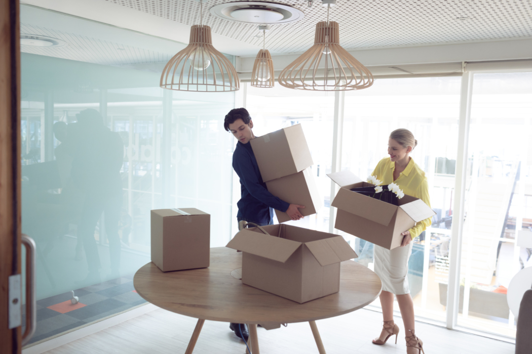 Front view of Caucasian male and female office executives holding cardboard boxes in office